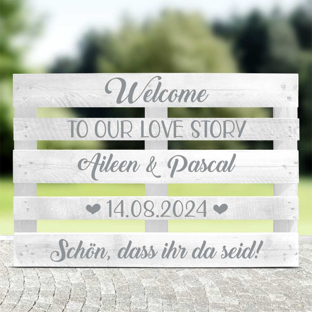 weisse Palette mit silberner Schrift "Welcome to our love story" für die Hochzeitsfeier